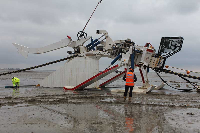 Sea Cable Plough
A man is standing next to a large piece of electrical equipment in the sand, with cables nearby.