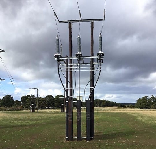 Electricity pylon with insulators against a cloudy sky.
