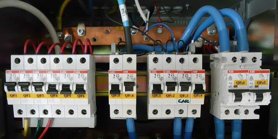 Close-up of an electrical panel displaying several circuit breakers, labeled with yellow tags such as QF1, QF2, and QF6, and connected by various colored wires.